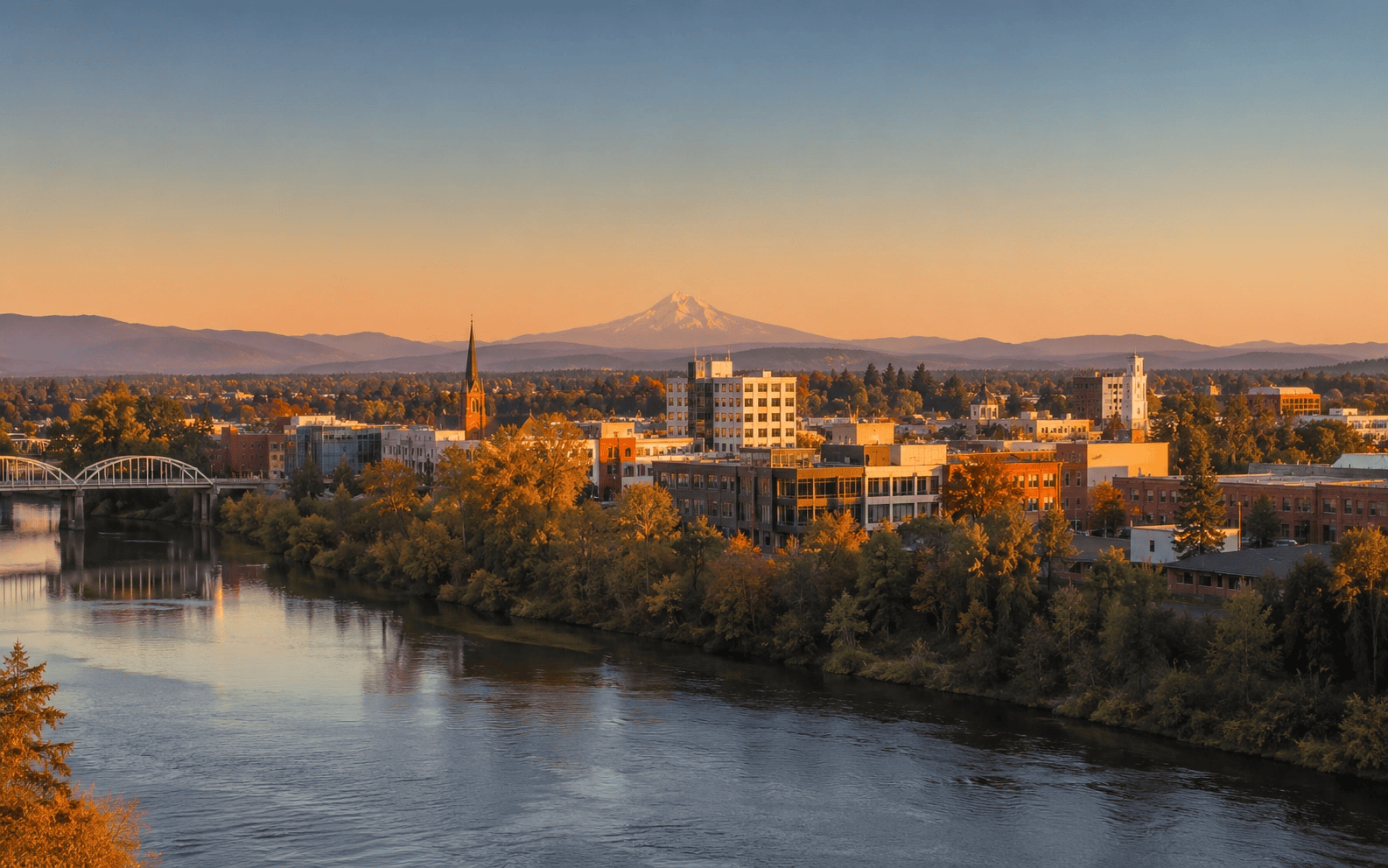 Wide editorial photograph of Albany Oregon skyline at golden hour with river bend in foreground.