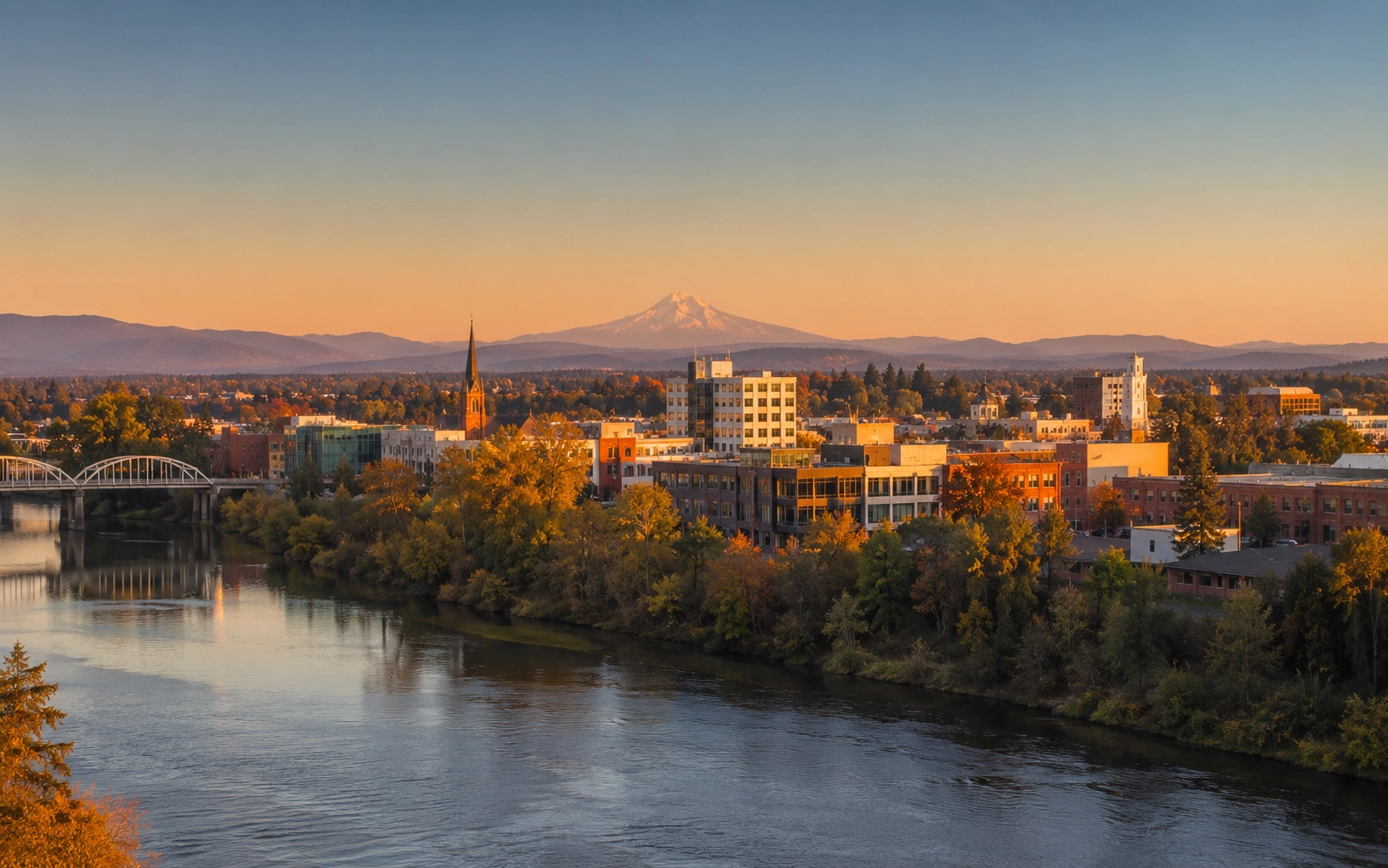 Wide editorial photograph of Albany Oregon skyline at golden hour with river bend in foreground.